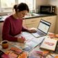 Woman planning Europe trip at cluttered kitchen table