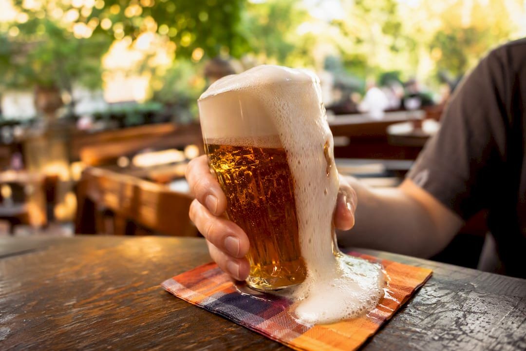 Hand holding Czech beer glass with dense foam