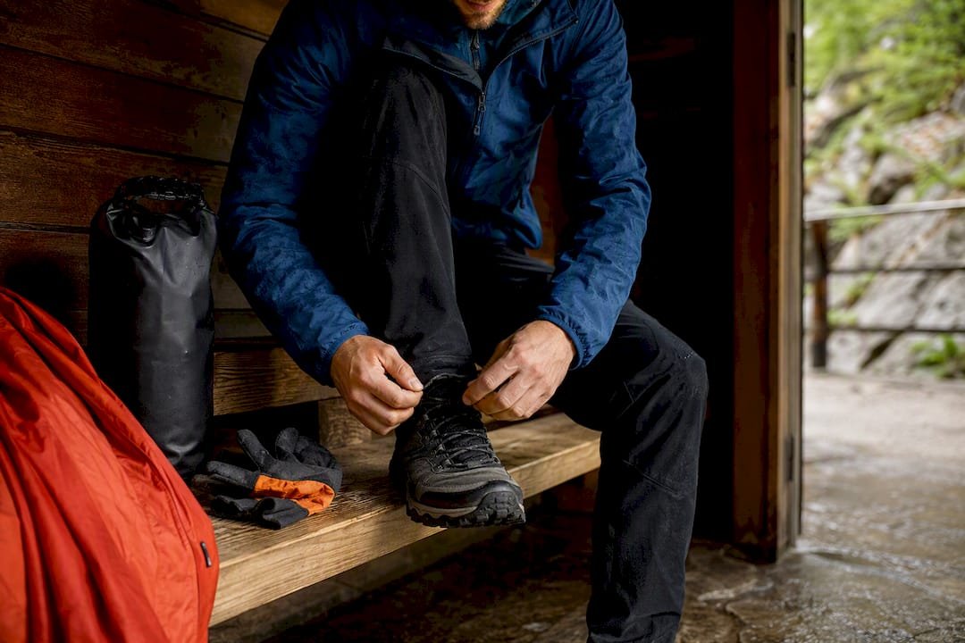 Hiker preparing boots gloves and dry bag
